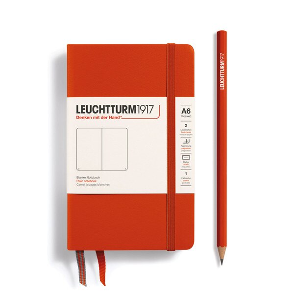 This is a small, red-orange notebook with an elastic and two bookmarks. The pages are blank other than page numbers in the bottom corners.